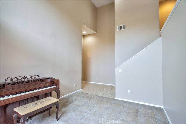 misc room featuring light tile patterned flooring and a high ceiling