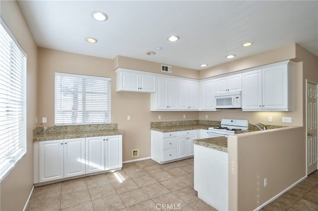 kitchen with light tile patterned floors, white appliances, and white cabinetry