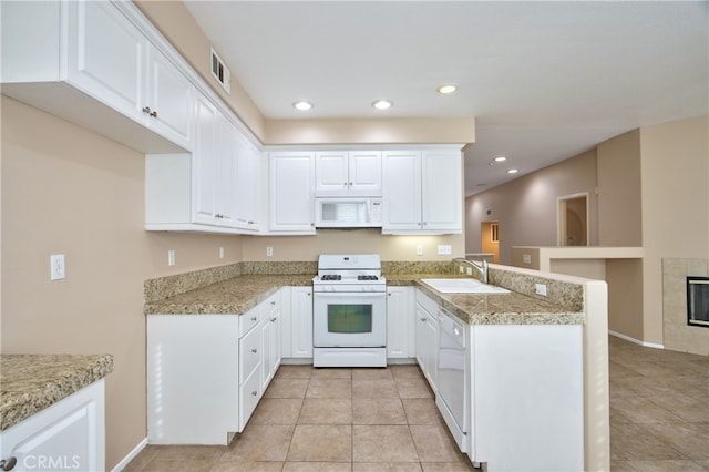 kitchen with white cabinetry, sink, white appliances, and kitchen peninsula