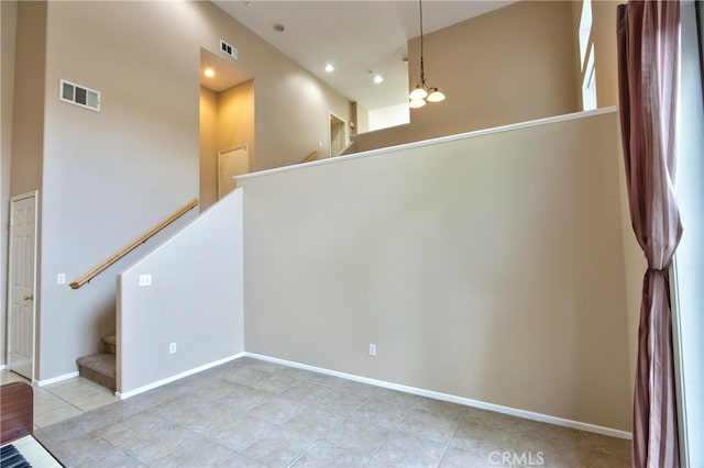 tiled empty room featuring a chandelier and a towering ceiling