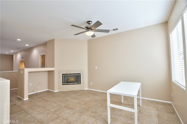 unfurnished living room with ceiling fan and a tiled fireplace