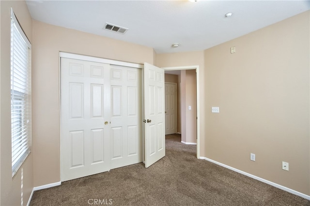 unfurnished bedroom with a closet and dark colored carpet