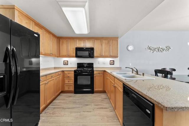 kitchen featuring sink, kitchen peninsula, light hardwood / wood-style flooring, light stone countertops, and black appliances