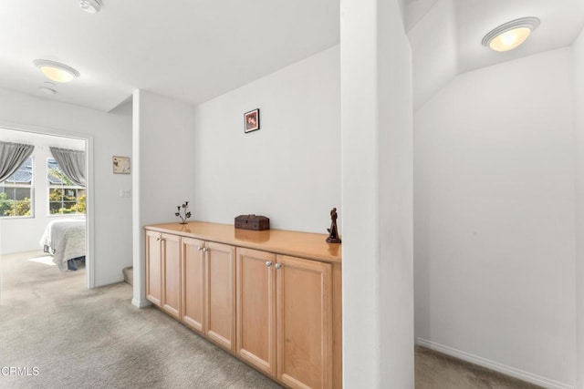 corridor with light carpet and lofted ceiling