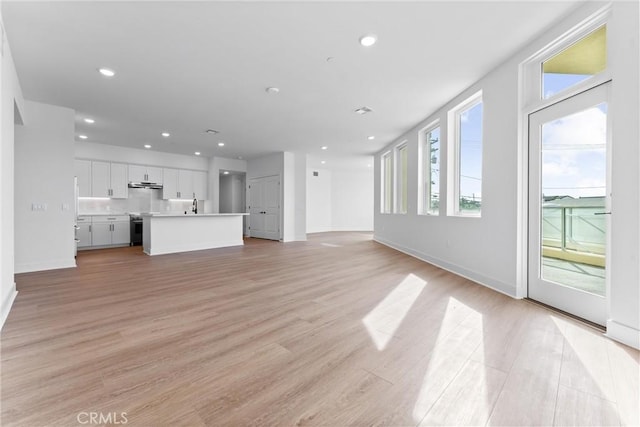 unfurnished living room with sink and light wood-type flooring