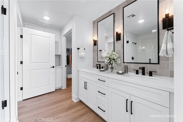 bathroom with walk in shower, vanity, and hardwood / wood-style floors