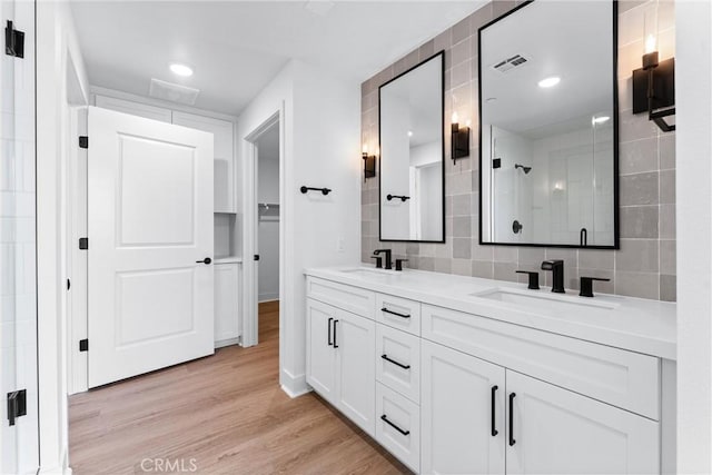 bathroom featuring vanity, backsplash, hardwood / wood-style flooring, and tile walls