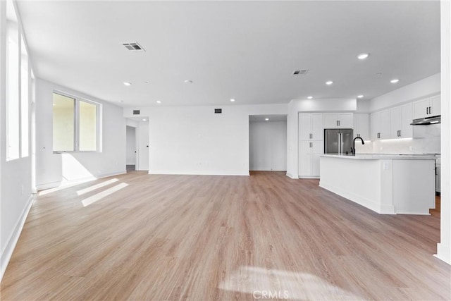 unfurnished living room featuring sink and light wood-type flooring