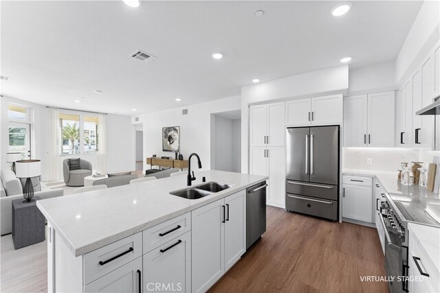 kitchen featuring dark wood-type flooring, sink, high quality appliances, a kitchen island with sink, and white cabinets