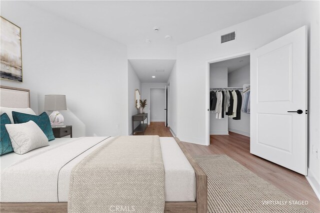 bedroom featuring light hardwood / wood-style flooring, a walk in closet, and a closet