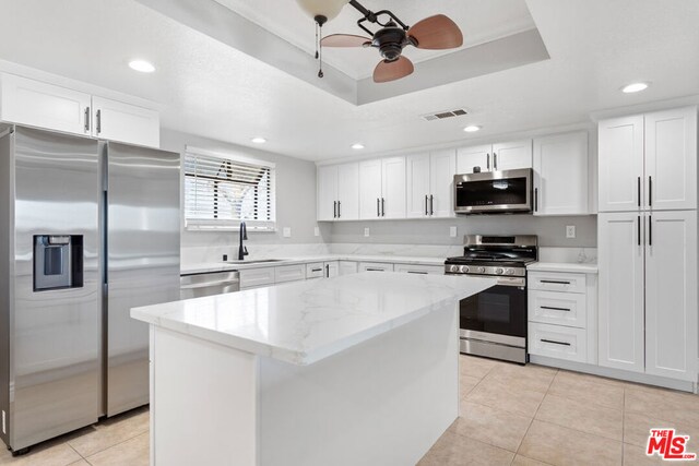 kitchen with appliances with stainless steel finishes, sink, white cabinetry, and a center island