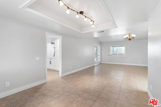 spare room with light tile patterned floors, ceiling fan with notable chandelier, a tray ceiling, and a textured ceiling