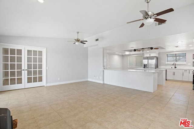 unfurnished living room featuring vaulted ceiling, ceiling fan, light tile patterned floors, and sink