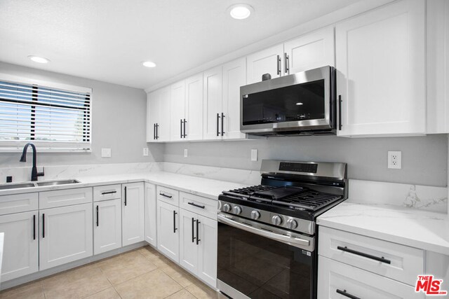 kitchen featuring light stone countertops, sink, white cabinets, and appliances with stainless steel finishes