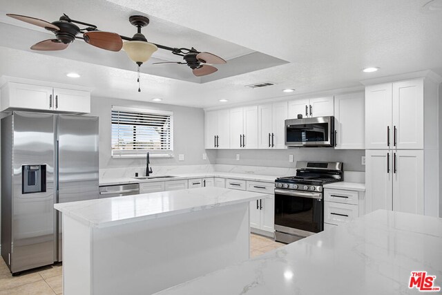 kitchen featuring light stone countertops, stainless steel appliances, white cabinetry, and sink