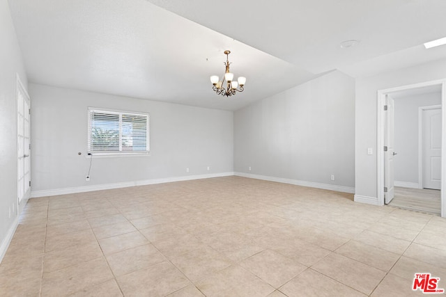 empty room featuring light tile patterned floors and a chandelier