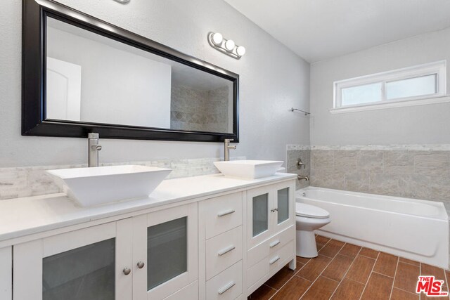 bathroom featuring toilet, a bathing tub, and vanity