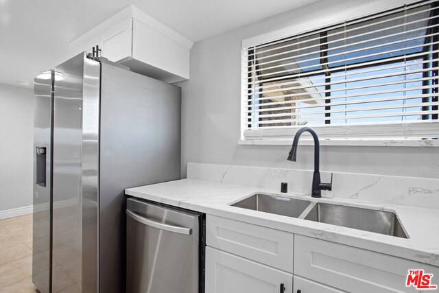 kitchen with white cabinets, light stone countertops, sink, and stainless steel appliances