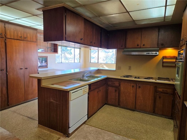 kitchen with exhaust hood, kitchen peninsula, white appliances, a paneled ceiling, and sink