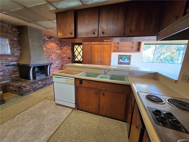 kitchen with brick wall, white dishwasher, cooktop, a drop ceiling, and sink