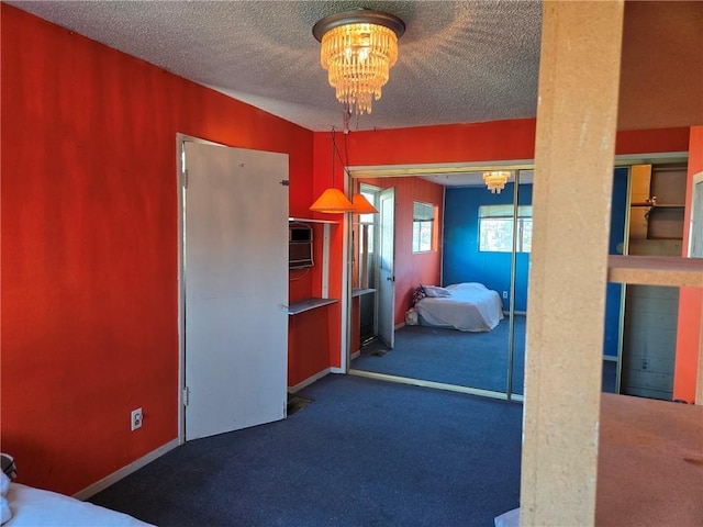 bedroom with a closet, an inviting chandelier, dark carpet, and a textured ceiling