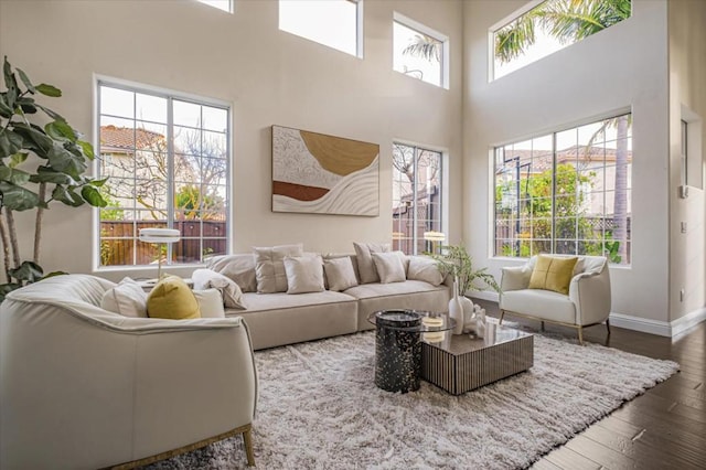 living room featuring a high ceiling, dark wood-type flooring, and a wealth of natural light