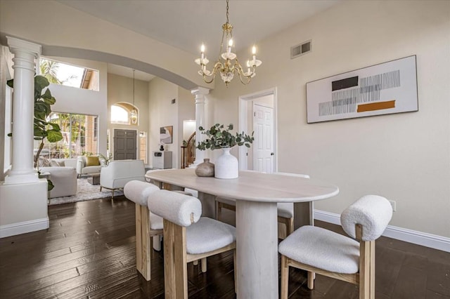 dining room featuring dark wood-type flooring, an inviting chandelier, and decorative columns