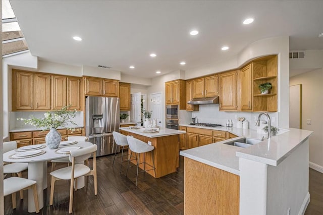 kitchen with stainless steel appliances, sink, kitchen peninsula, dark hardwood / wood-style floors, and a breakfast bar