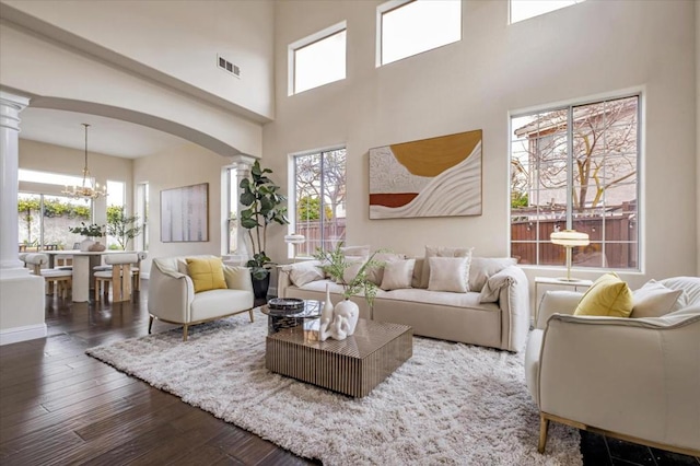 living room with a notable chandelier, a healthy amount of sunlight, and ornate columns