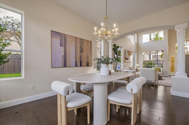 dining area featuring dark wood-type flooring, an inviting chandelier, and ornate columns