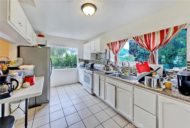 kitchen with light tile patterned floors, white cabinetry, tasteful backsplash, white gas range, and sink