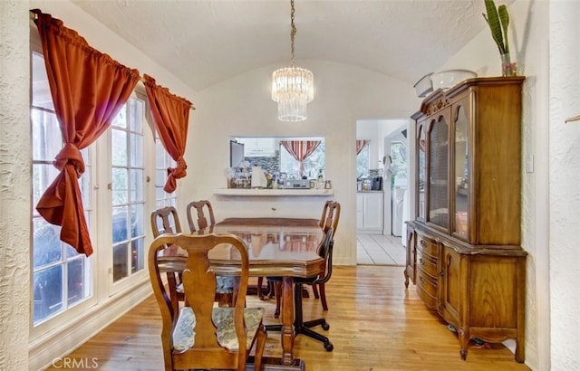 dining space featuring brick ceiling, light hardwood / wood-style flooring, lofted ceiling, and a chandelier