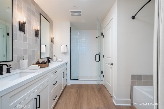 414 Main St Unit 310, Huntington Beach, CA 92647 - full bathroom featuring a stall shower, wood finished floors, tile walls, double vanity, and a tub to relax in