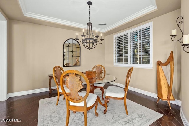 dining space featuring ornamental molding, a raised ceiling, a chandelier, and dark hardwood / wood-style flooring