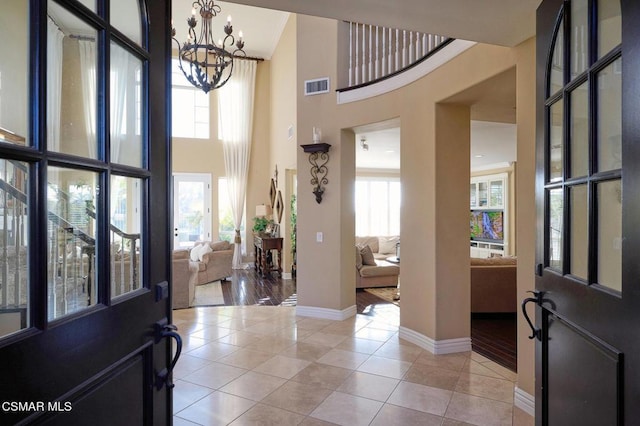 tiled foyer entrance with a towering ceiling, an inviting chandelier, and a healthy amount of sunlight