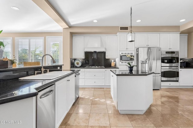 kitchen with stainless steel appliances, sink, decorative light fixtures, premium range hood, and a kitchen island