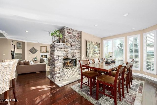 dining area with ornamental molding, dark hardwood / wood-style flooring, and a fireplace