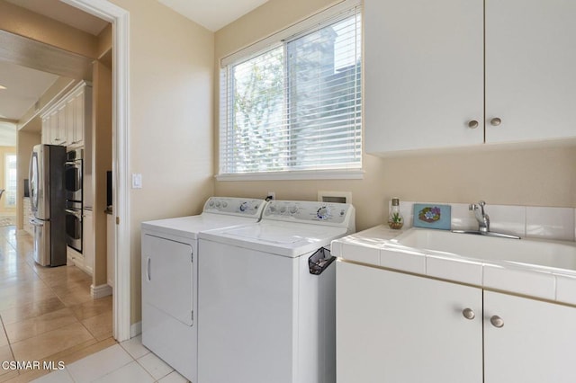 clothes washing area featuring washer and dryer, cabinets, light tile patterned flooring, and sink