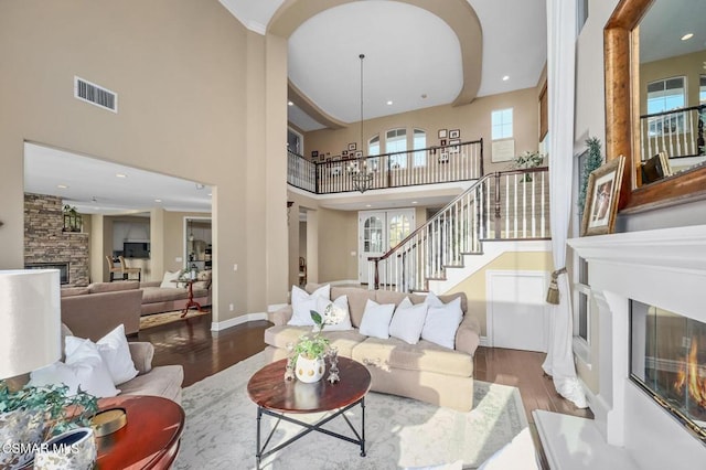 living room featuring a high ceiling, wood-type flooring, and a stone fireplace