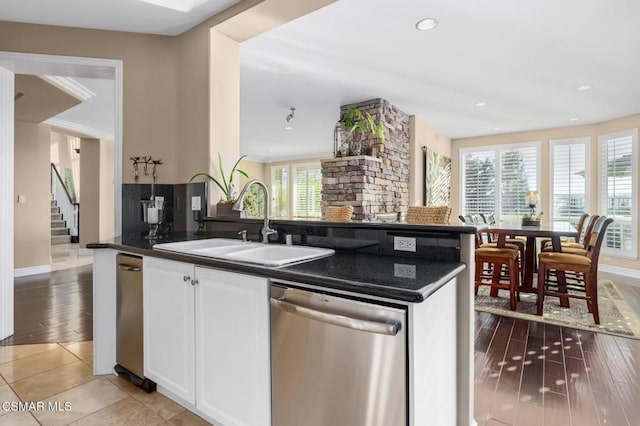 kitchen featuring plenty of natural light, white cabinets, stainless steel dishwasher, and sink