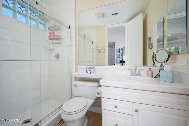 bathroom featuring toilet, vanity, tile patterned floors, and a shower with shower door