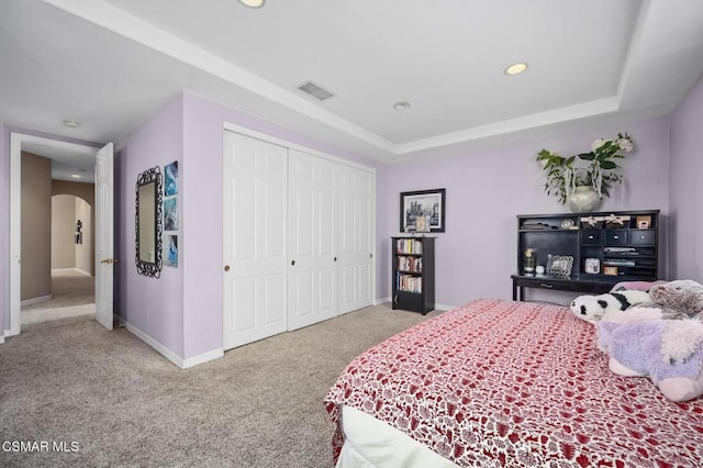 bedroom featuring light carpet, a closet, and a raised ceiling