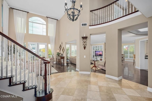 tiled entrance foyer with a high ceiling, ornamental molding, a chandelier, and a healthy amount of sunlight