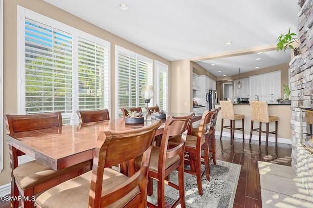 dining area featuring dark hardwood / wood-style flooring and a stone fireplace