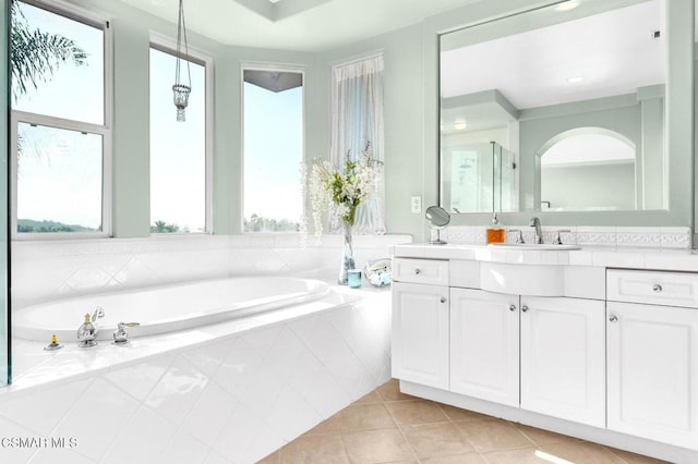 bathroom with tiled bath, tile patterned flooring, a healthy amount of sunlight, and vanity