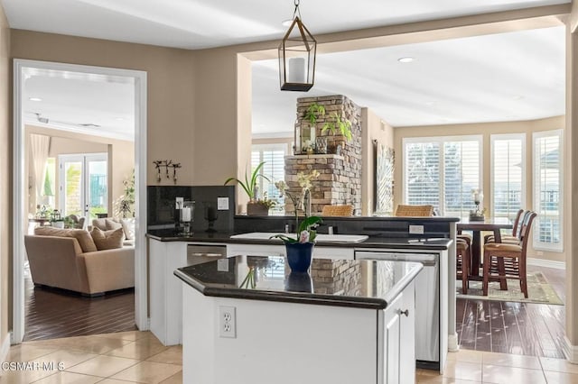 kitchen with sink, a center island, decorative light fixtures, and light tile patterned floors