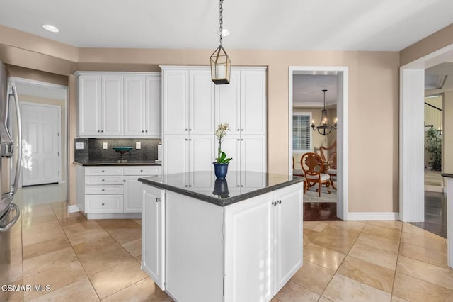 kitchen with decorative light fixtures, white cabinets, dark stone countertops, decorative backsplash, and a notable chandelier