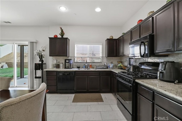 kitchen featuring sink, light stone counters, black appliances, dark brown cabinets, and backsplash