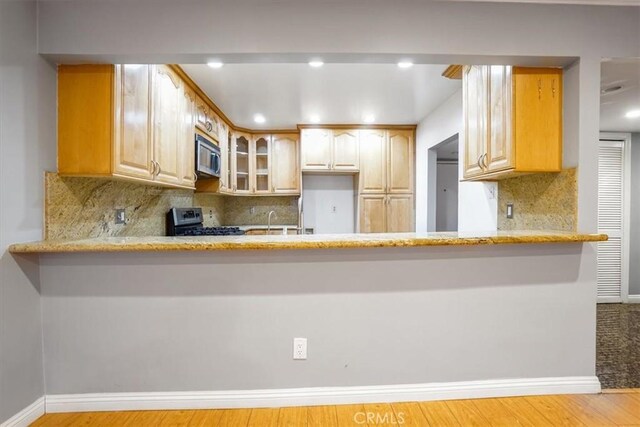 kitchen with light brown cabinetry, sink, kitchen peninsula, and stainless steel appliances