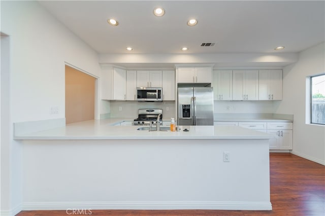 kitchen featuring hardwood / wood-style floors, kitchen peninsula, sink, stainless steel appliances, and white cabinets